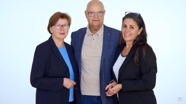 Ilse Fitzbauer, Harry Kopietz und Michaela Sramek in Businesskleidung stehen eng beieinander vor hellem Hintergrund und blicken in die Kamera.