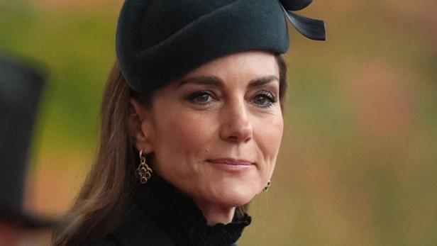 Prinzessin Catherine trägt einen dunklen Mantel und einen passenden Hut mit einer dekorativen Schleife.