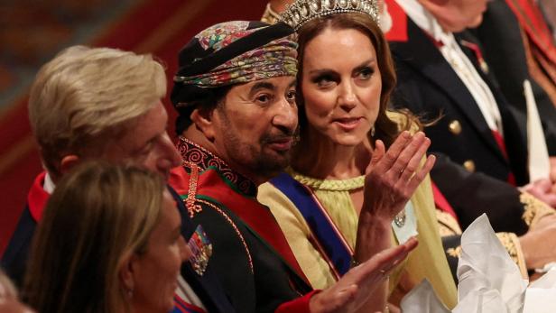 Catherine, Princess of Wales, trägt eine Tiara und sitzt neben einem Mann mit traditioneller Kopfbedeckung und Uniform bei einer Veranstaltung.