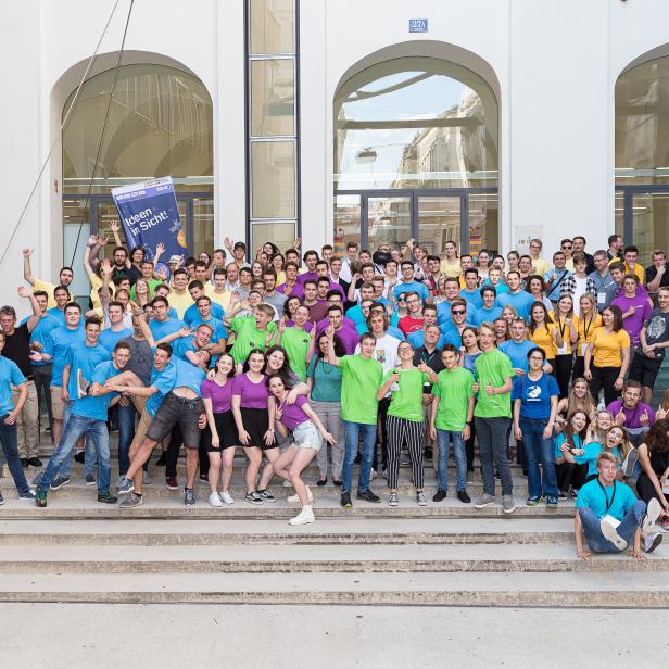 Eine große Gruppe junger Leute posiert auf einer Treppe vor einem Gebäude.