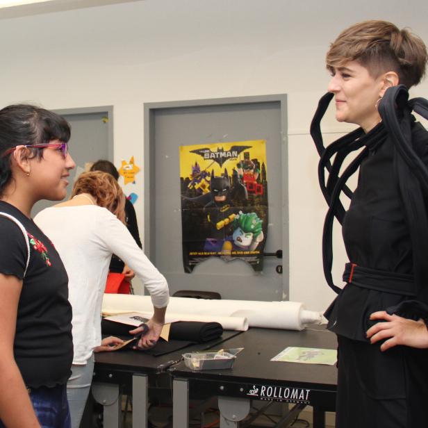 Zwei Frauen unterhalten sich in einem Raum mit einem „The Lego Batman Movie“-Poster.