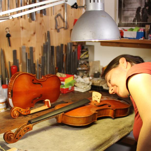 Eine Geigenbauerin arbeitet an einer Violine in ihrer Werkstatt.