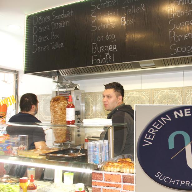 Ein Imbissstand mit Döner, Schnitzel, Hotdogs und anderen Speisen auf der Speisekarte.