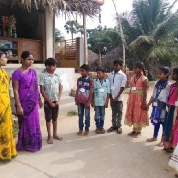 Eine Gruppe von Kindern und zwei Frauen stehen vor einem kleinen Laden.