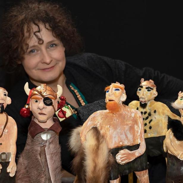 Eine Frau präsentiert eine Sammlung handgefertigter Puppen mit Wikinger- und Fantasiefiguren.