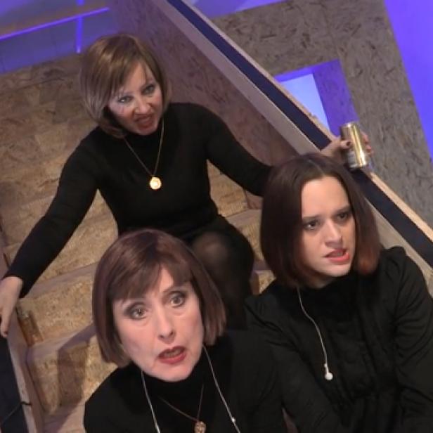 Drei Frauen stehen auf einer Holztreppe und schauen mit ernsten Gesichtsausdrücken in die Kamera.