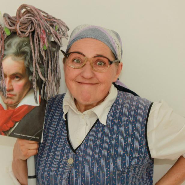 Frau Franzi posiert mit einem Bild von Beethoven, das mit einer Garnperücke verziert ist.