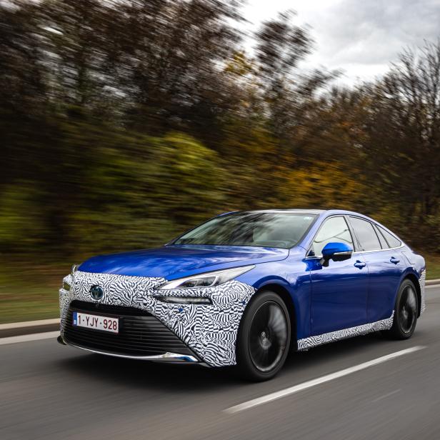 Ein blauer Toyota Mirai mit Zebra-Tarnmuster fährt auf einer Straße.