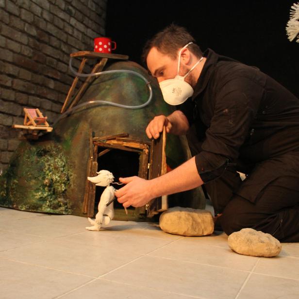 Puppenspieler mit einer Maulwurf-Figur vor dem Maulwurfhügel.