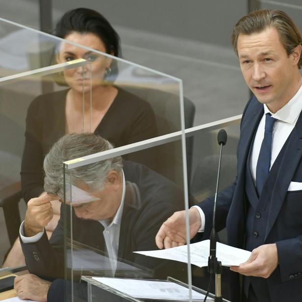 Ein Mann im Anzug hält ein Dokument bei einer Rede.