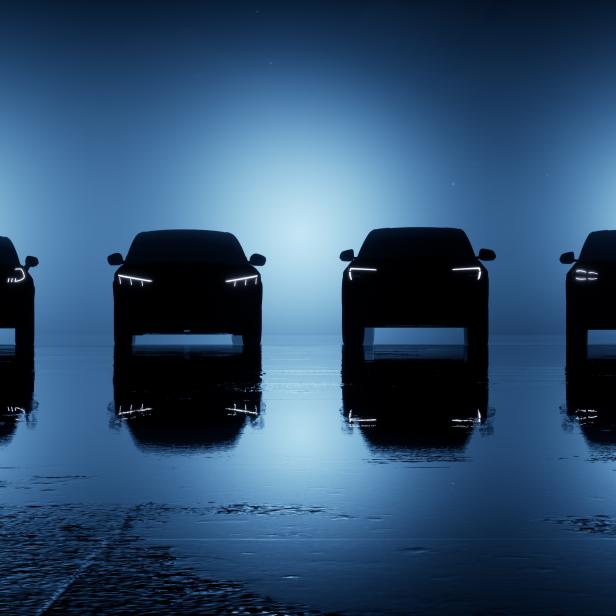 Vier dunkle Autos stehen auf einer nassen Oberfläche vor einem blauen Hintergrund.