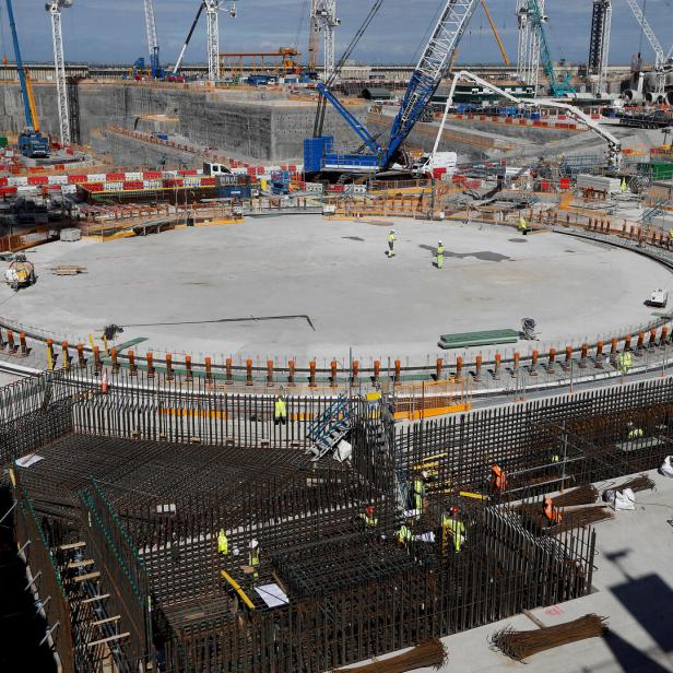 Bauarbeiter arbeiten auf einer großen Baustelle mit Kränen und Stahlbetonkonstruktionen.